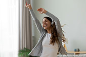 Woman wearing headphones dancing in living room at home