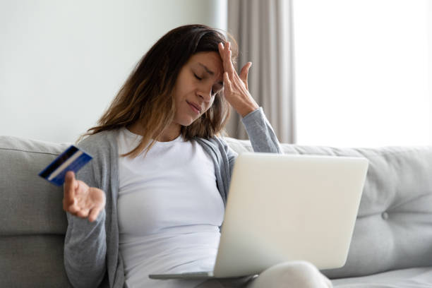 Woman feels stressed having access problem to e-banking Millennial woman sit on sofa feels stressed using laptop holding plastic credit card having access problem to e-banking service, wrong or forgot password, fraud and scam, cyber criminal victim concept operating budget stock pictures, royalty-free photos & images