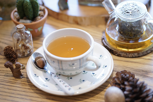 Afternoon tea. English afternoon tea with herbal tea. Selective focus on the acorn. Teapot is on the background. Fall concept with pine cones and acorn,