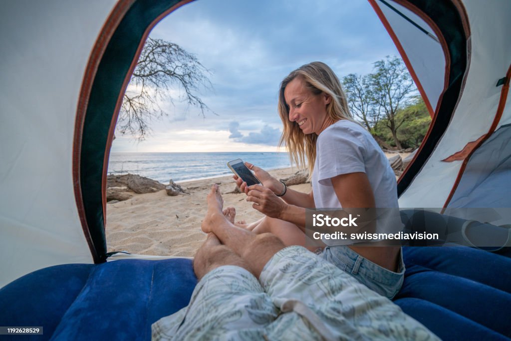 Jong Stel Binnen Tent Met Mobiele Telefoon Twee Personen Op Het Strand Stockfoto meer beelden van Natuur -
