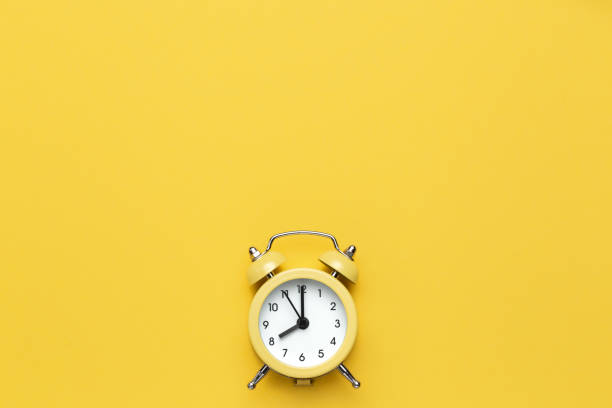 istock Yellow round alarm clock on the yellow background. 1192635065