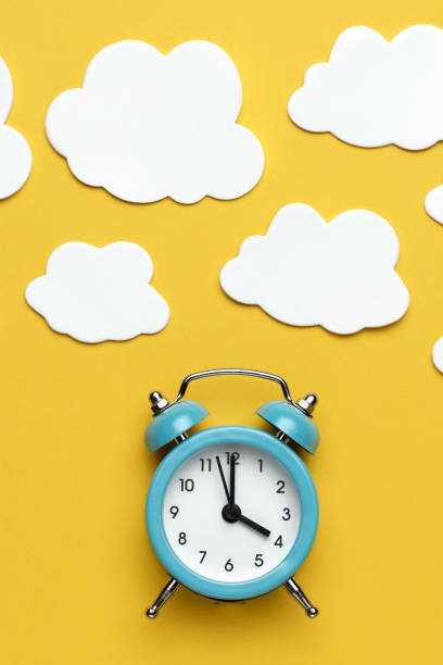 istock Blue round alarm clock and white cloud on the yellow background. 1192635104