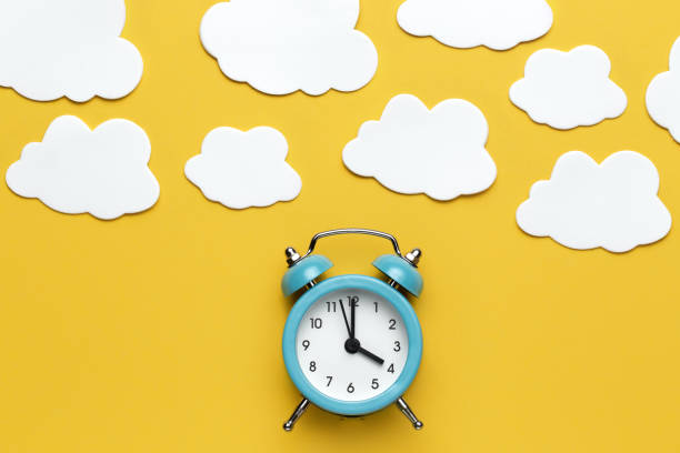 istock Blue round alarm clock and white cloud on the yellow background. 1192635129