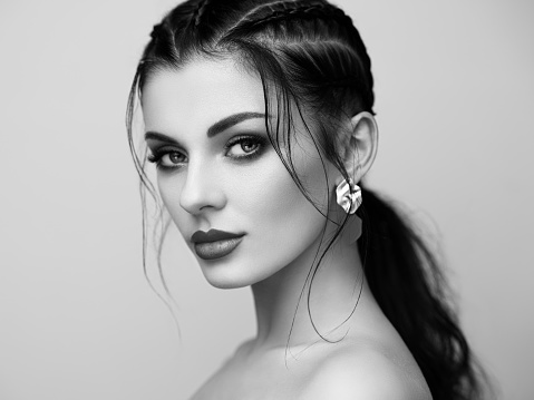 Brunette girl with perfect makeup. Beautiful model woman with curly hairstyle. Care and beauty hair products. Lady with braided hair. Model with jewelry. Black and white photo