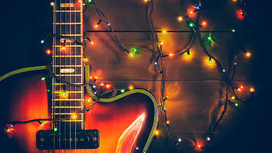 Old, jazz electric guitar with a luminous garland. New Year greeting card for musician, guitarist. Festive background.