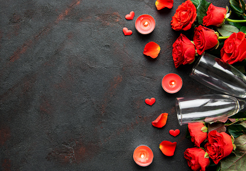Valentines day romantic background - red roses, glasses, candle and hearts. Flat lay, copy space.