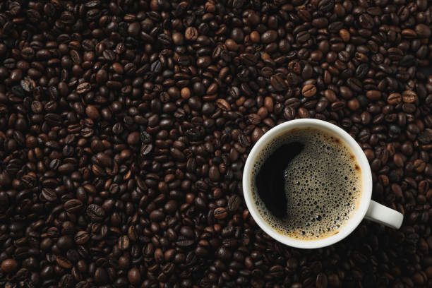 istock Cup of coffee on coffee beans background, top view 1192637109