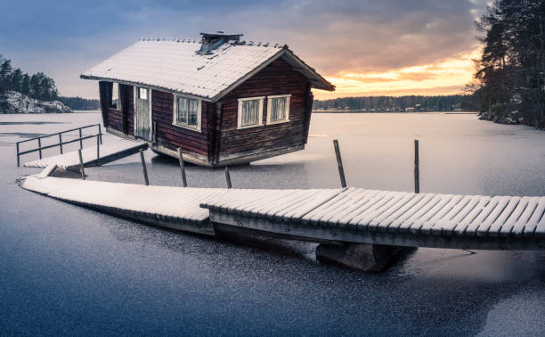 sauna abandonné et jetée cassée avec le paysage de coucher du soleil au soir d'hiver en finlande - finland sauna lake house photos et images de collection