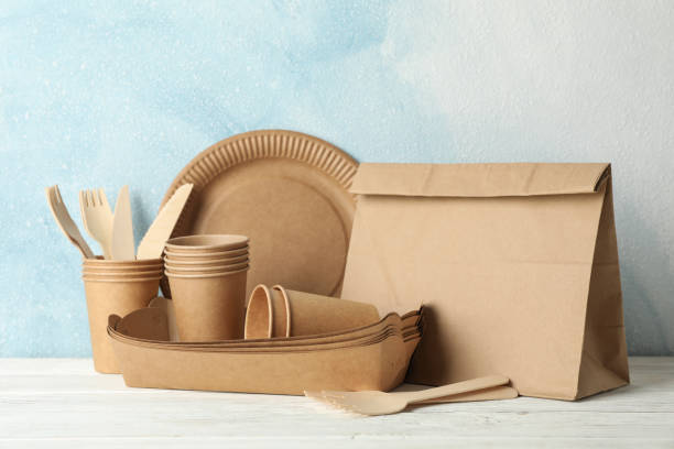 istock Eco - friendly tableware and paper bag on wooden table, space for text 1192639202