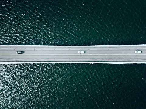 Aerial top view of bridge road with cars over lake or sea in Finland