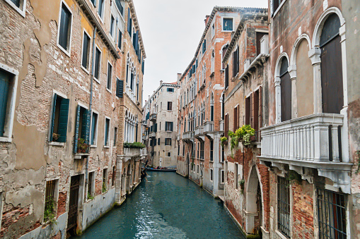 Venice, Italy - October 18, 2019: A photo of a small boat navigating through the canals of Venice in Italy. Venice is a city in northeastern Italy and the capital of the Veneto region. It is situated on a group of 118 small islands that are separated by canals and linked by over 400 bridges. Parts of Venice are renowned for the beauty of their settings, their architecture, and artwork, and the City is also known for several important artistic movements, especially during the Renaissance period.