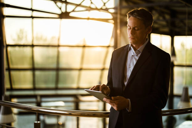 istock Businessman reading an e-mail on touchpad in a hallway. 1192646988