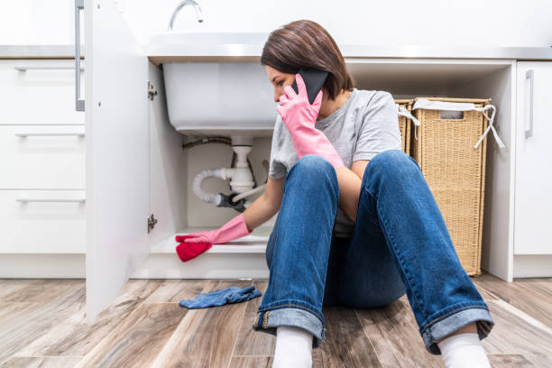 istock Woman sitting near leaking sink in laundry room calling for help 1192647816