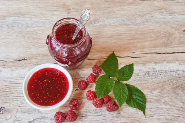 istock Raspberry jam and fresh raspberry with green leves on a rustic wooden table 1192647899