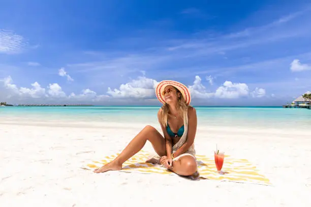 Photo of Happy woman relaxing on a beach towel in summer day.