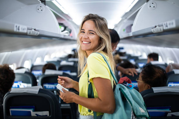 Young happy woman in an airplane cabin. Happy woman boarding the airplane and looking at camera. airplane interior stock pictures, royalty-free photos & images