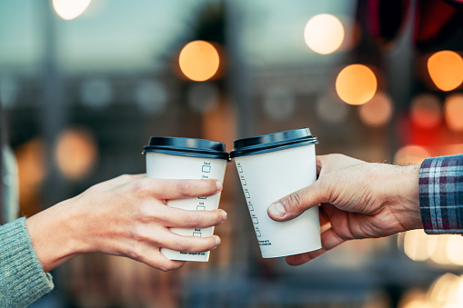 a couple is toasting with paper cup and drink coffee.
