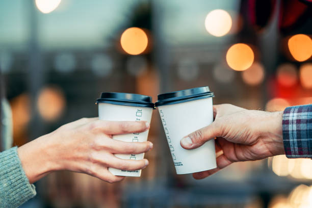 a couple is toasting with paper cup and drink coffee stock photo