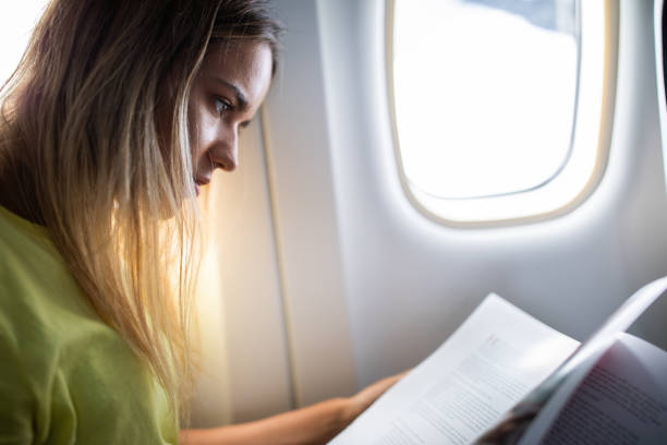 istock Young woman reading a book in an airplane. 1192650280