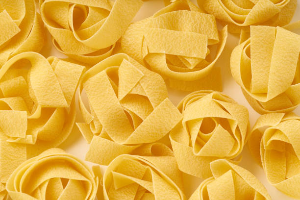 白い背景に生のパパルデルパスタの巣でクローズアップ - pappardelle ストックフォトと画像