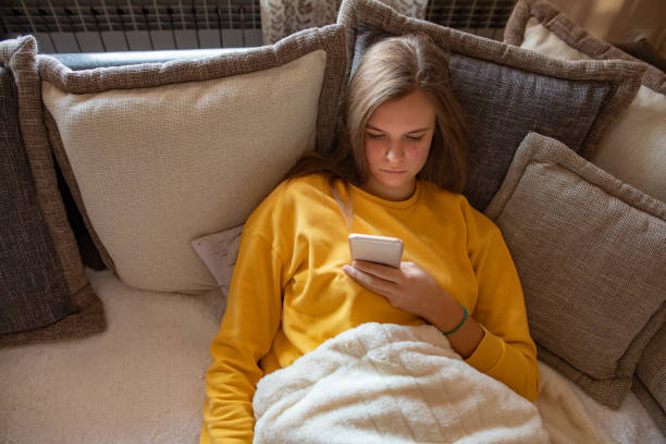 istock Young woman using mobile phone on sofa in the morning 1192655073