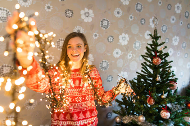 istock Young woman looking at the Christmas light decorating tree in her home 1192655152