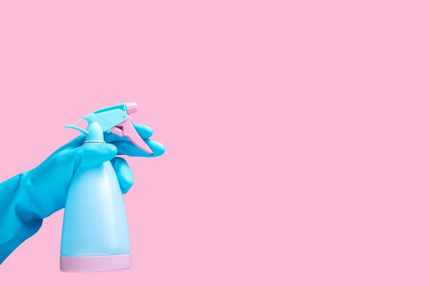 mano in guanto di gomma blu che tiene pulito spray bottiglia detergente isolato su sfondo rosa con spazio di copia per testo o logo - kitchen glove foto e immagini stock