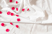 Top view of pink rose petals on white bed sheets on honeymoon. Surprise romantic concept background