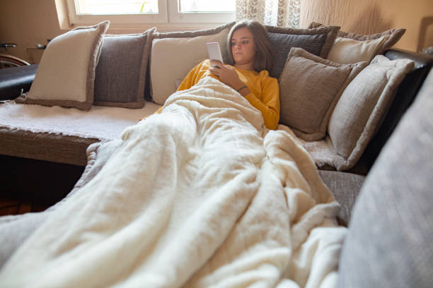 istock Young woman using mobile phone on sofa in the morning 1192656322