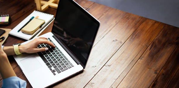 istock Mockup image of a woman using laptop with blank screen on wooden table 1192656357