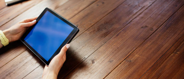 istock Mockup image of a woman using digital tablet with blank screen on wooden table 1192656369