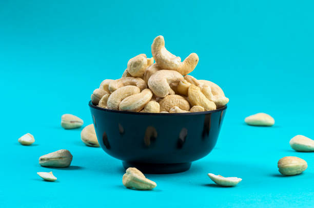 파란색 배경에 그릇에 캐슈 너트 - cashew close up food salted 뉴스 사진 이미지