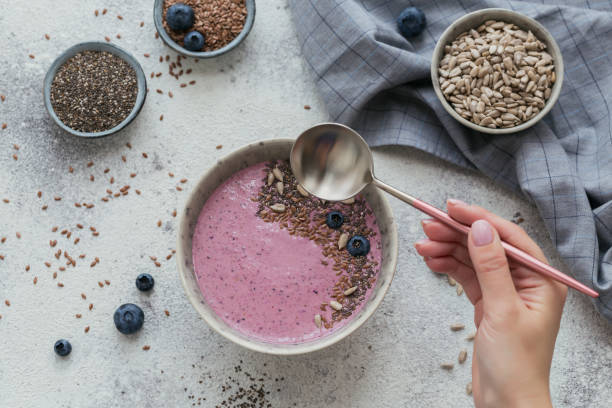 woman's hands holding pink yogurt smoothie bowl made with fresh berry and seeds - vitality food food and drink berry fruit imagens e fotografias de stock