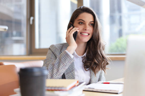 istock Young smiling business woman using smartphone near computer in office. 1192660007