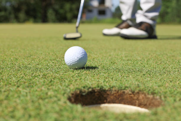 istock Golf player at the putting green hitting ball into a hole. 1192661120