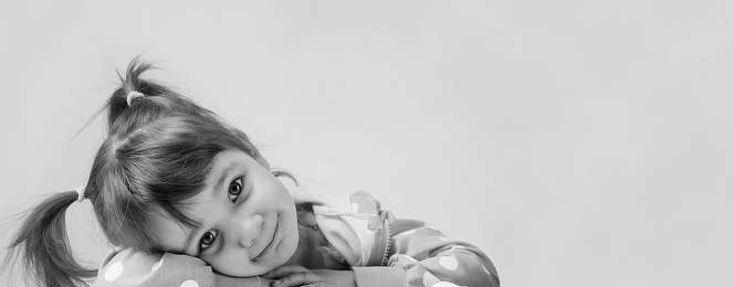 A black and white portrait of a three year old girl in her room