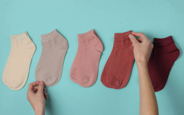 istock Female hand folds a colored socks on blue background. Top view 1192662849