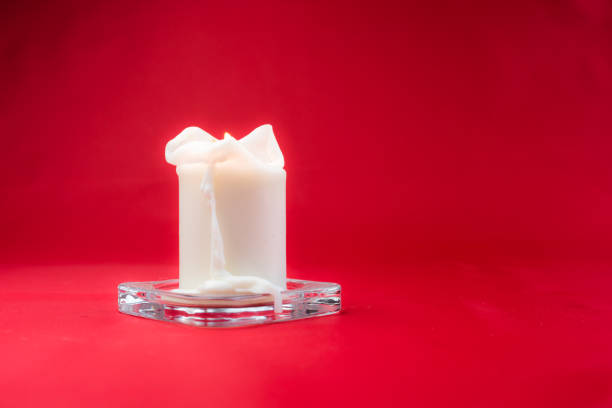 Isolated burning candle on bright vivid red background
