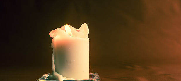 Front view of red color candle with flame with white color background.