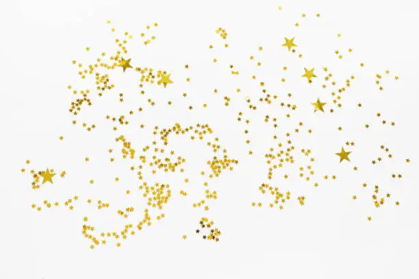 Golden stars confetti abstract pattern on white background. Celebration concept, top view.