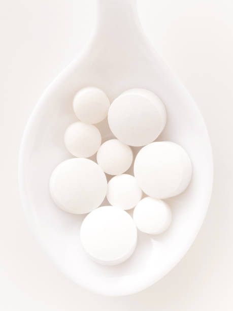 pilules blanches - vitamin pill vertical high key photographic effects photos et images de collection