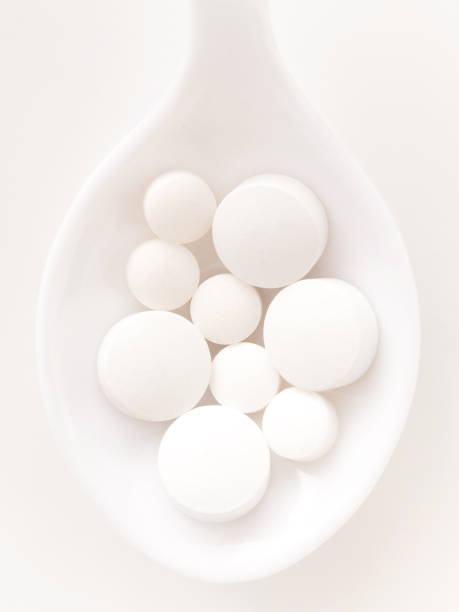 белые таблетки - vitamin pill vertical high key photographic effects стоковые фото и изображения