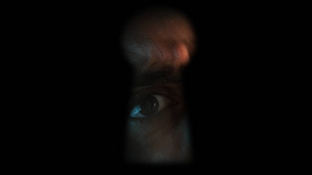 Close up of shocked male eye looking through a keyhole Close up of shocked male eye looking through a keyhole peep hole stock pictures, royalty-free photos & images