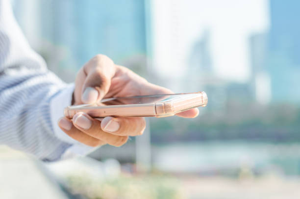 istock close up business man using hand typing smartphones and touch screen working search with app devices outdoor in city with sunrise and building background. 5G technology connecting the world. 1192681705