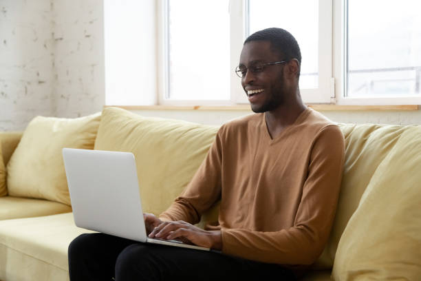 istock Smiling african American man using laptop in living room 1192686746