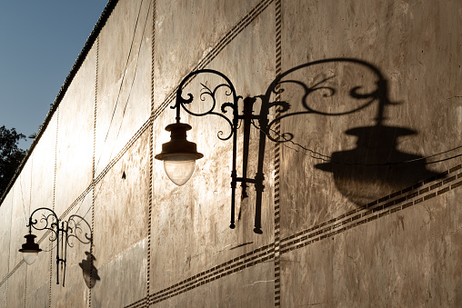 Warm sunlight on a wall. Ornate lanterns casting dark shadows in Fez, Morocco