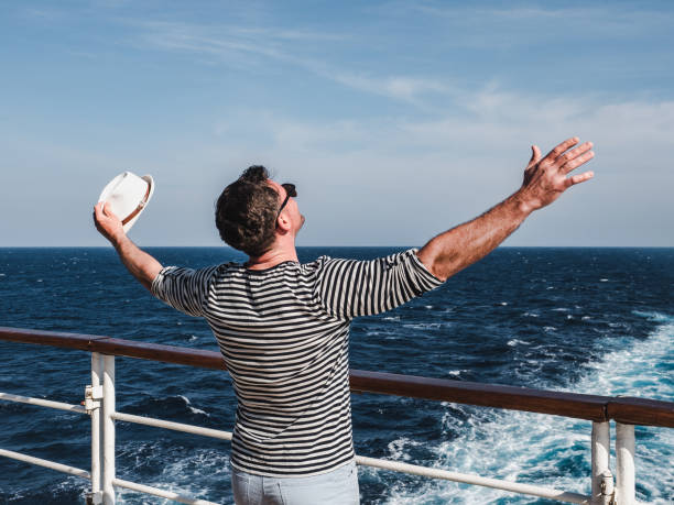 Smiling man on the empty deck of a liner Smiling man on the empty deck of a cruise liner on the background of sea waves. Top view, close-up. Concept of leisure and travel cruise ship people stock pictures, royalty-free photos & images