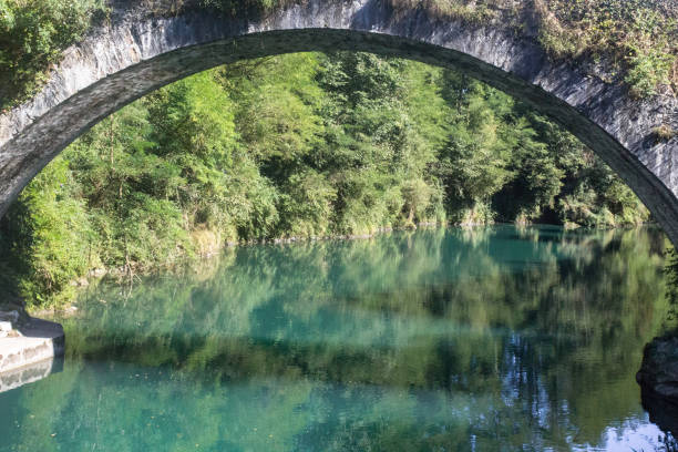 istock Reflection of a forest in a mountain river under an arched bridge 1192696237