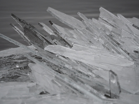Clear ice washed up on the river shore like shards of glass. Background pattern close up.