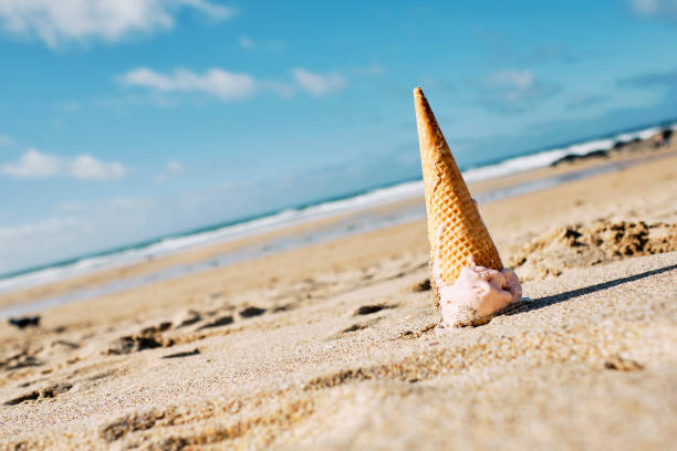 istock Dropped strawberry flavoured Ice cream cone on the sand. 1192698982